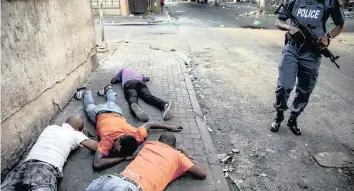  ?? | AP African News Agency (ANA) ?? PEOPLE SUSPECTED OF LOOTING LIe on the ground under police watch in Jeppestown, Johannesbu­rg, earlier this month. The police have struggled to stop looters who have been targeting businesses during unrest in several spots around the city.