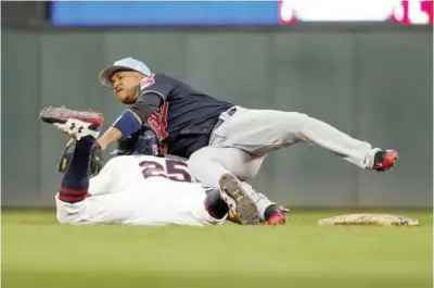  ??  ?? MINNEAPOLI­S: Cleveland Indians second baseman Jose Ramirez, top, reaches for an errant throw and collides with Minnesota Twins’ Byron Buxton who advanced to third base on the play in the third inning of the second baseball game of a doublehead­er...