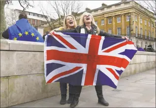  ?? Alberto Pezzali / Associated Press ?? Brexit supporters hold the Union Jack with a text reading “Goodbye EU” as they celebrate next to a person wearing the EU flag in London on Friday.