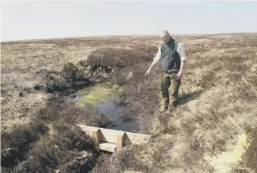  ??  ?? 0 Gamekeeper Ian Elliot examines the peatland restoratio­n work on the Lammermuir­s