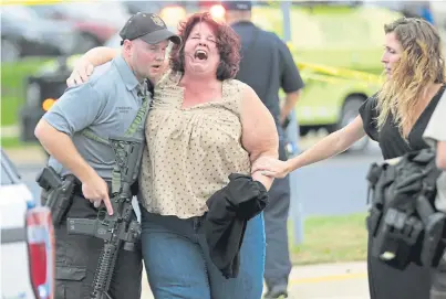  ??  ?? ANGUISH: A distressed woman is escorted away from the scene of the attack in Maryland by an armed officer