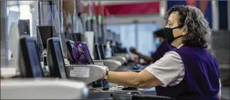  ?? ALYSSA POINTER / ALYSSA.POINTER@AJC.COM ?? A Delta Air Lines employee works behind plexiglass in May. If the workforce reduction is not enough, Delta CEO Ed Bastian told CNBC, more could be coming. But, he said, “I’m optimistic if we do have a furlough, it’s going to be relatively minimal numbers.”