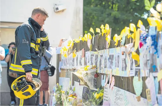  ??  ?? A firefighte­r views tributes after observing a minute’s silence at Latymer Community Centre, near to Grenfell Tower.