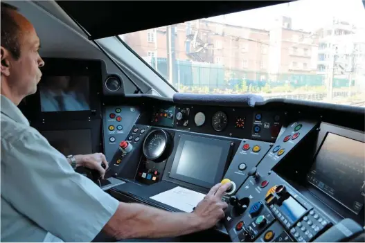  ?? RICHARD CLINNICK. ?? Driver Mike Fortune at the controls of Great Western Railway 800034. The screen in the centre is for the European Train Control System (ETCS), although that has yet to be commission­ed. To his left is the Automatic Train Protection (ATP) screen. The screen on the right is the Train Management System (TMS). Fortune’s left hand is on the power handle, which is also the brake handle. On the right can be a seen a blue button casing, with a red button below it - these are the pantograph controls that enable the Class 800 to switch power supply.