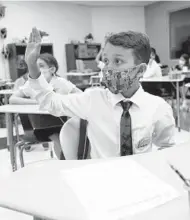  ?? LYNNE SLADKY/AP ?? Student Winston Wallace, 9, raises his hand in class on the first day of school Monday in Miami, where schools opened with a strict mask mandate.