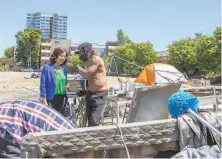  ?? Photos by Nina Riggio / Special to The Chronicle ?? Above: City Council President Nikki Fortunato Bas speaks with Aideen, a homeless man, about plans for a project to be built at the Oakland lot on which he has lived for the past year. Right: Bas examines a makeshift tent with Krystal, who also resides at the encampment near Lake Merritt.