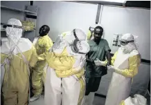  ?? JOHN WESSELS ?? HEALTH workers embrace while putting on their protective equipment before heading to work at an MSF-supported Ebola treatment centre. |