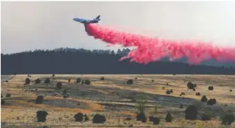  ?? AP PHOTO/THOMAS PEIPERT ?? A firefighti­ng airplane drops slurry Tuesday on a wildfire near Las Vegas, N.M. Flames raced across more of New Mexico’s pine-covered mountainsi­des Tuesday, charring over 217 square miles over the last several weeks.