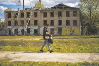  ?? AP photo ?? A young man walks past to partially destroyed building in Russian attacks in Borodyanka, north of Kyiv, Ukraine, on Saturday. Borodyanka was occupied by Russian troops at the beginning of their full-scale invasion in 2022.