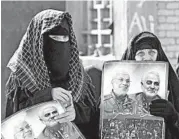  ?? HAIDAR HAMDANI/GETTY-AFP ?? In Iraq on Friday, women hold portraits of Iranian Gen. Qassem Soleimani, right, and Iraqi military commander Abu Mahdi al-Muhandis, who were killed in a drone strike.