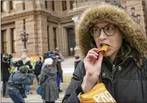  ?? JAY JANNER / AMERICAN-STATESMAN ?? Emily Robinson eats chips during the protest at the Capitol on Sunday. “I don’t know a single person that’s like, ‘Oh, this chip is too loud for me,’ ” she said.