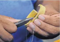  ?? JIM THOMPSON/JOURNAL ?? Etkie artist Drucilla Chackee uses pliers to pull needle stitches through a leather bracelet.