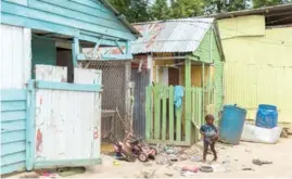  ??  ?? Un niño juega con restos de juguetes en un patio del batey.