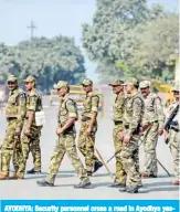  ??  ?? AYODHYA: Security personnel cross a road in Ayodhya yesterday, as a Supreme Court issues verdict on a disputed religious site. — AFP