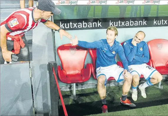  ?? FOTO: UNCITI ?? Zurutuza, sentado junto a Sandro en San Mamés, estrecha la mano de un aficionado del Athletic en el banquillo de los visitantes