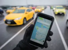  ?? CP FILE PHOTO ?? The Uber app is displayed on an iPhone as taxi drivers wait for passengers at Vancouver Internatio­nal Airport on March 7.