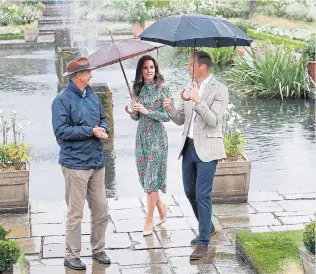  ??  ?? Kate and William shelter under umbrellas visiting The Sunken Garden yesterday