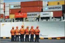  ?? THE ASSOCIATED PRESS ?? Chinese workers stand in front of a loaded cargo ship docked at a port in Qingdao in east China’s Shandong province on Sunday.