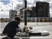  ?? EPA ?? A woman lays flowers near the 14-storey tower that was hit by fire. Authoritie­s believe the building’s cladding could have exacerbate­d the blaze