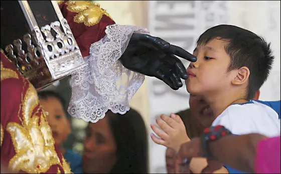  ?? AP ?? A boy kisses the hand of the Black Nazarene in Quiapo, Manila ahead of the celebratio­n of the feast day on Tuesday.