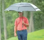  ?? ADAM CAIRNS/DISPATCH ?? Jon Rahm holds an umbrella while lining up a shot in the rain at the 2020 Memorial.