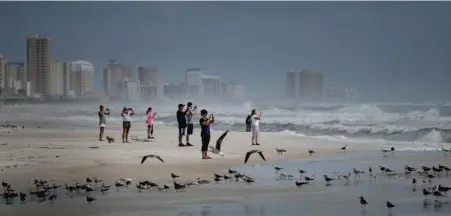  ?? BRENDAN SMIALOWSKI/AFP-GETTY ?? People look out to the Gulf of Mexico as Hurricane Michael approaches in Panama City Beach.