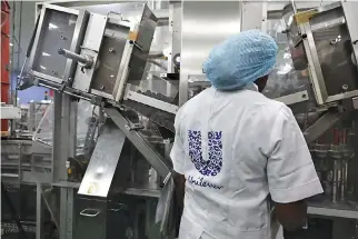  ??  ?? A WOMAN stands behind a machine that is part of a toothpaste manufactur­ing line at the Unilever factory in Lagos, Nigeria on Jan. 18.