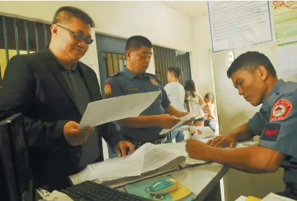  ?? SUNSTAR / ARNI ACLAO ?? TRANSFER. Atty. Gerardo Carillo (left) hands his client Bohol PB Member Niño Rey Boniel's commitment order to the Talibon District Jail to personnel of the Fuente Police Station.