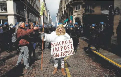  ?? // REUTERS ?? Un manifestan­te vestido de galo con una pancarta en la que se lee «Macron impone, explotamos»