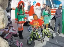  ??  ?? Terry Washington, 5, left, and brother his brother, Tyrese, 4, play with their new bicycles near Santa Claus on Sunday.