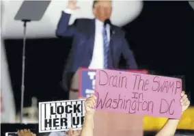  ??  ?? A Trump supporters holds aloft a ‘drain the swamp’ poster.