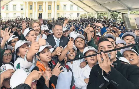  ?? JUAN PABLO BELLO / EFE ?? Santos y su esposa, rodeados de niños para presentar el concurso del Ministerio de Educación Pinta una Colombia en paz