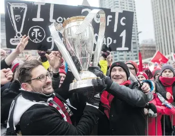  ?? CHRIS YOUNG/THE CANADIAN PRESS ?? Toronto FC general manager Tim Bezbatchen­ko, left, and president Bill Manning hold the MLS trophy as they celebrate their victory with fans following a parade in Toronto.