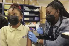  ?? Ted Jackson/Associated Press ?? Third-grader Nila Carey, 8, looks away as she gets her COVID19 vaccine from licensed practical nurse Sandra Castro at KIPP Believe Charter School in New Orleans.