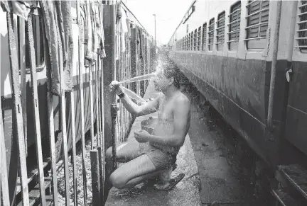  ?? CHANNI ANAND/THE ASSOCIATED PRESS FILES ?? An train passenger takes a bath on a hot summer day at a railway station in Jammu, India.