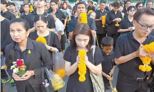  ?? AP-Yonhap ?? Thai mourners line up in front of a portrait of the late Thai King Bhumibol Adulyadej to pay respects outside the Grand Palace in Bangkok, Thailand, Friday. Thais marked one year since the King with formal ceremonies and acts of personal devotion...