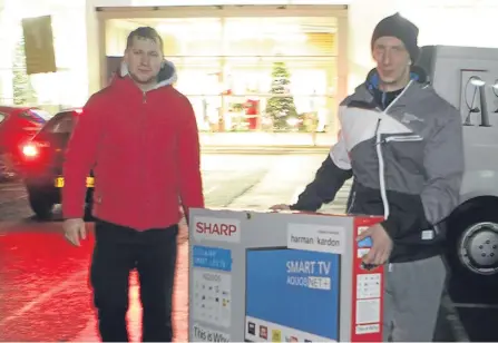  ??  ?? Marcin Butowski and David Myotk carry out a TV from Tesco’s Kingsway store.