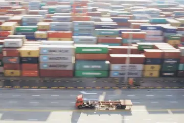  ??  ?? A truck drives past container boxes at the Yangshan Deep Water Port, part of the Shanghai Free Trade Zone in Shanghai. — Reuters photo