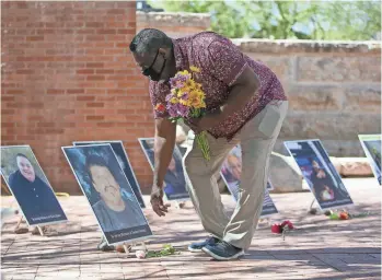  ?? MEG POTTER/THE REPUBLIC ?? Todd Bailey sets flowers down in front of photos of people who have died of COVID-19 in the courtyard of the Arizona Heritage Center at Papago Park on Monday.