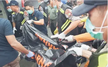  ??  ?? Indonesian policemen carry a body bag containing the remains of a passenger on board the ill-fated Lion Air flight JT 610, at the Jakarta port in Jakarta.