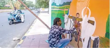  ?? Agence France-presse ?? ↑
An artist paints a mural, depicting a farmer on his bullock cart, in New Delhi on Tuesday.