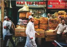  ?? Bloomberg ?? Pedestrian­s walk past stalls selling food outside the Jama Masjid at night in the Old Delhi area of New Delhi.