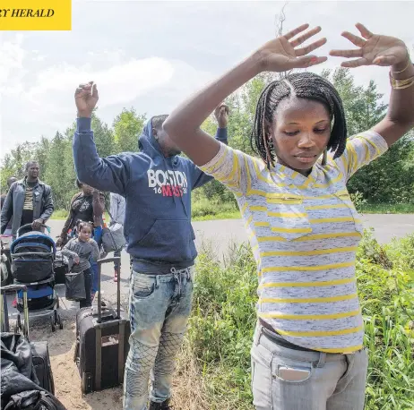  ?? RYAN REMIORZ / THE CANADIAN PRESS FILES ?? Asylum seekers approach RCMP officers while crossing the Canadian border at Champlain, N.Y., last August.