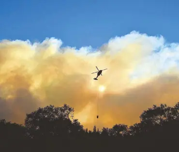  ?? AFP ?? A helicopter makes a water drop in the Feather River Canyon, east of Paradise, California on Sunday.