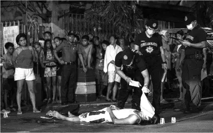 ?? AGENCE FRANCE PRESSE ?? In this photograph taken on October 3, 2017, police personnel surround the body of an alleged drug user killed in Manila.