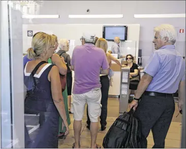  ?? THANASSIS STAVRAKIS / ASSOCIATED PRESS ?? Customers line up inside an Alpha Bank branch inAthens as banks reopened Monday inGreece for the first time in three weeks. But strict controls on cash flows, including a ban on check-cashing and payments abroad aswell as limits on cash withdrawal­s, remained in effect.