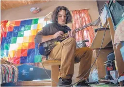  ?? EDDIE MOORE/JOURNAL ?? Thomas Gray, 19, who is Mohawk, performs a song on his guitar after a news conference at which he talked about an incident at Colorado State University. He and his brother were detained by police for being too quiet during a campus tour. He was at his...
