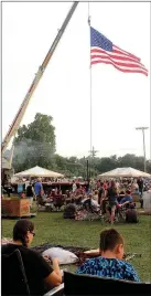  ??  ?? The American flag, suspended from a fire engine, flutters above patriotic people enjoying watermelon, music, family and friends.