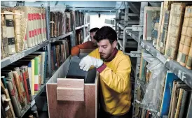  ??  ?? Workers put rare books into boxes at the historic National Library of Greece. The old Vallianeio building will be stored and still be used to hold library archives and events.
— AFP