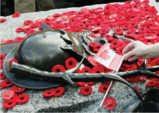  ?? CP PHOTO/TOM HANSON ?? Every Remembranc­e Day, visitors cover the Tomb of the Unknown Soldier at the National War Memorial with a mantle of crimson poppies.